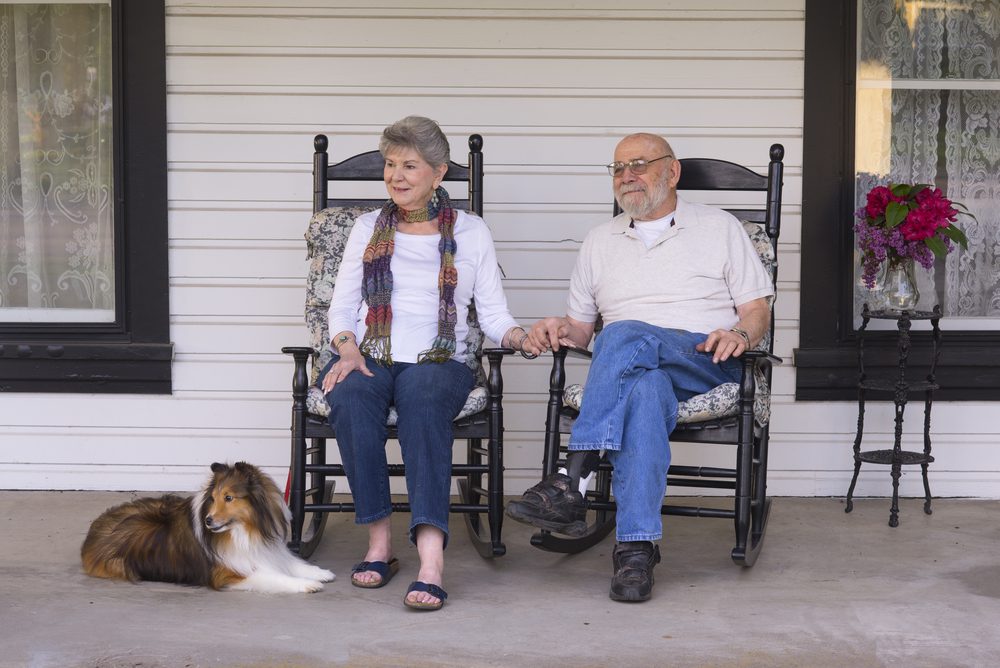 An elderly married couple in their eighties watch the world go by from their porch
