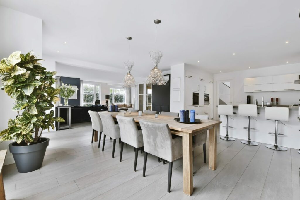 A minimalist dining room with two chandeliers hanging over a wooden table